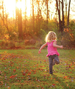 A little girl runs in a field. 