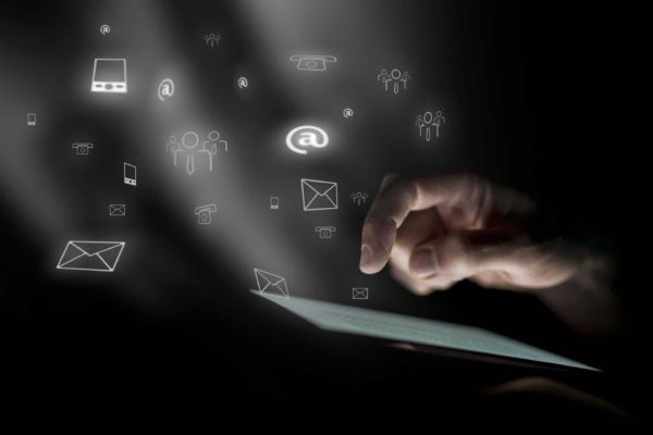 The Most Important Types of Emails You Need for Email Marketing Success Hand hovering over ipad with social media and email icons hovering in the air.