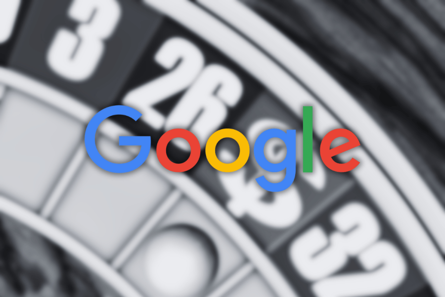 A blurred roulette wheel with numbered red, black, and green pockets appears in the background, overlaid with the multicolored Google logo in sharp focus at the center. Google takes aim at sweepstakes games, removing 'social' classification. Google announces update of Gambling and Games Policy including ads restrictions across 35 countries
